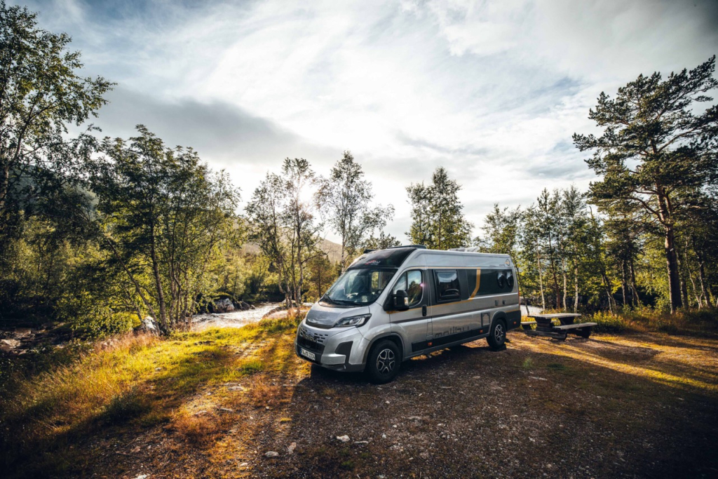 Ansicht eines Malibu Campervans in der Natur vor einem Bach.