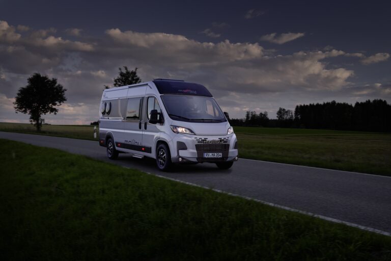 Malibu Campervan first-class-two-rooms bei Dämmerung auf einer Landstraße.