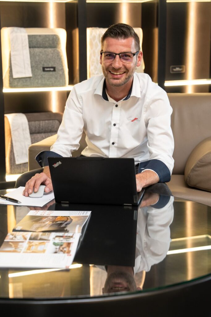 Ein lachender Malibu-Verkäufer mit einem Laptop vor sich.