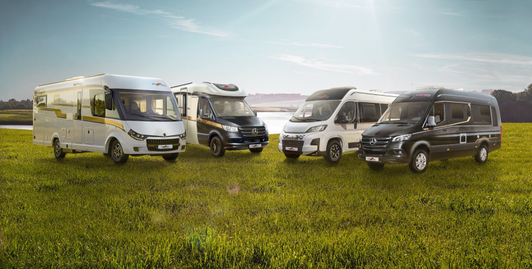 Zwei Malibu Reisemobile und zwei Malibu Campervans auf einer Wiese vor einem See.
