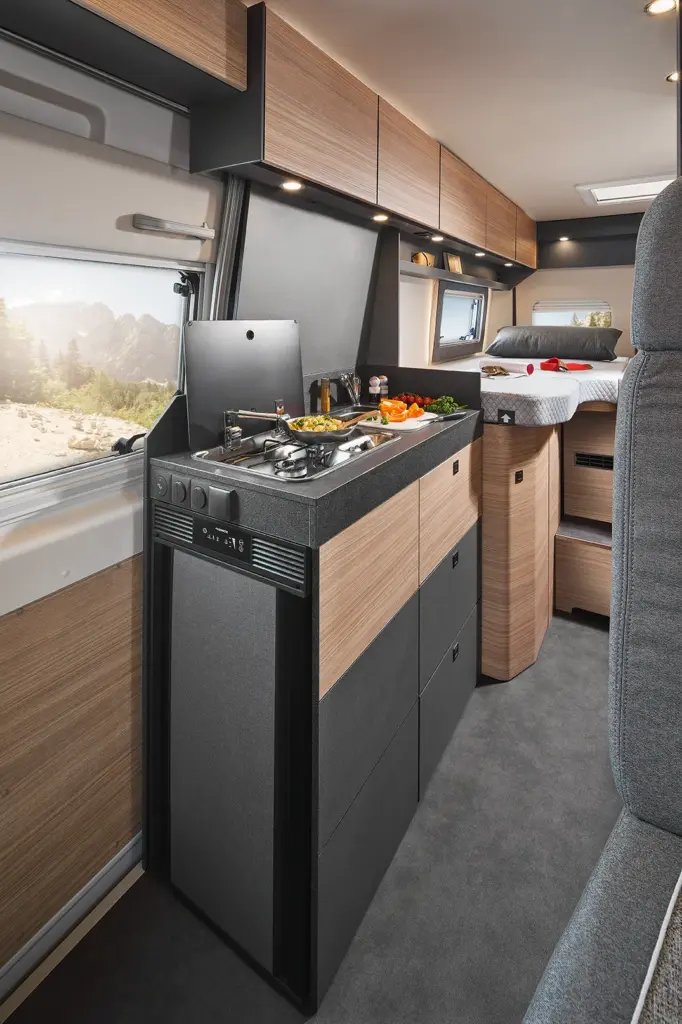 Cuisine intégrée moderne avec vue panoramique dans le camping-car Malibu Van : compacte, fonctionnelle et élégante