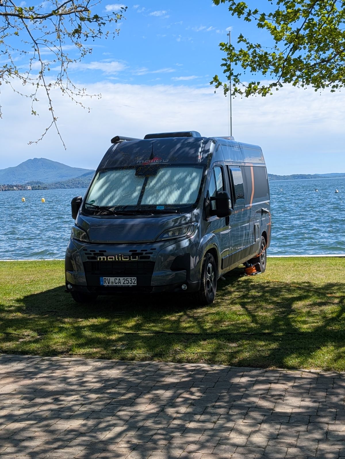 Ansicht eines Malibu Van vor einem See in Italien.