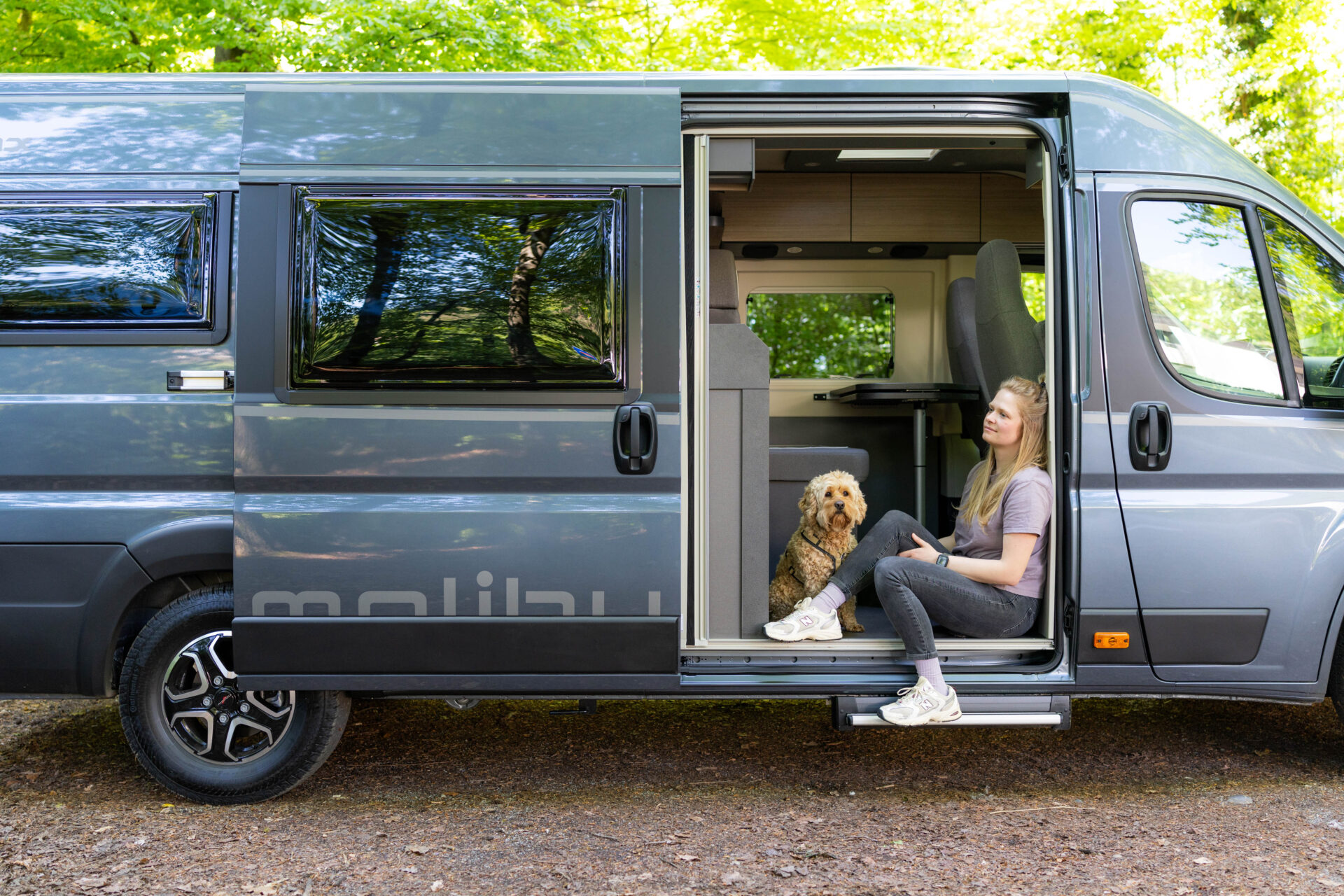 Malibu Relax Camper Van mit geöffneter Schiebetür – entspannter Moment mit Hund in der Natur