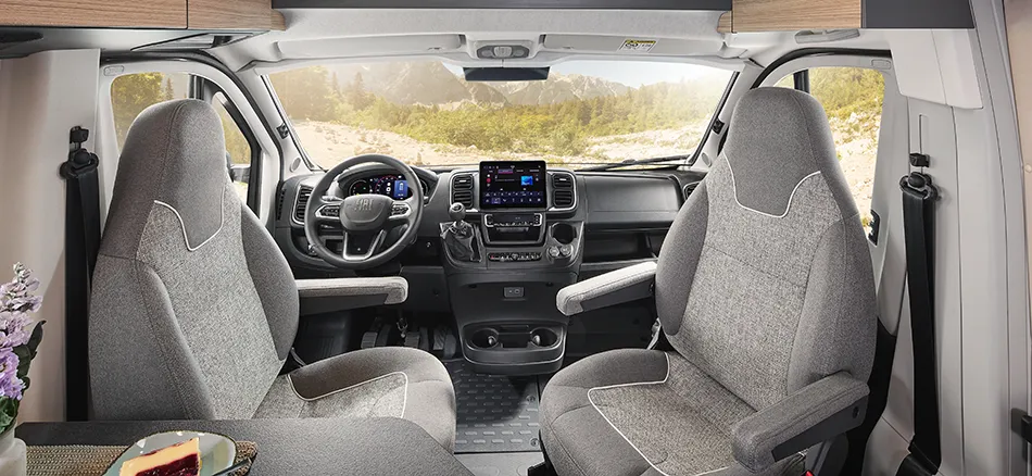 Modernes Cockpit und gemütlicher Sitzbereich im Malibu Camper Van mit Blick auf die Berge