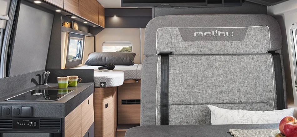 Kompakte Küche und gemütlicher Schlafbereich im Malibu Camper Van mit durchdachtem Stauraum