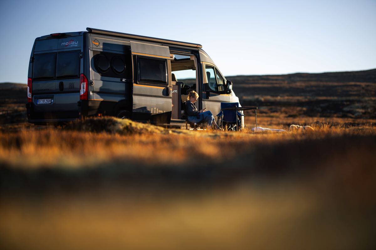 Ein Malibu Van steht mit geöffneter Türe in Norwegen auf einer Wiese