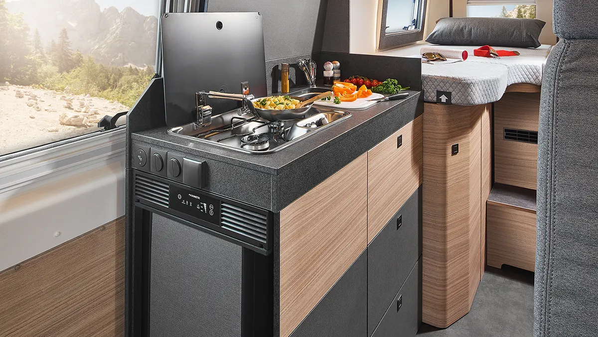 Voll ausgestattete Küchenzeile im Malibu Relax Camper Van mit Gaskocher, Spüle, Kühlschrank und frischen Zutaten für die Zubereitung von Pasta