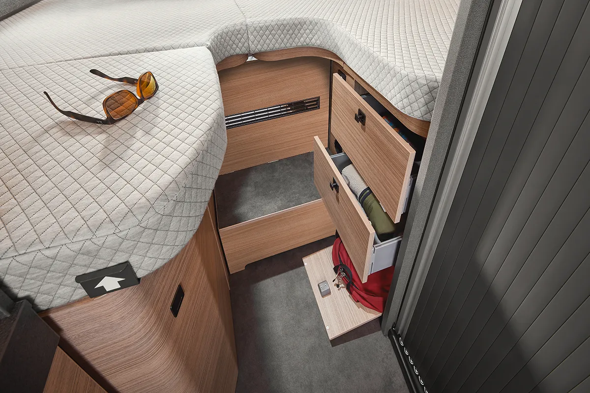 Schlafbereich im Malibu Relax Camper Van mit komfortabler Matratze und integrierten Schubladen für Kleidung und Reiseutensilien