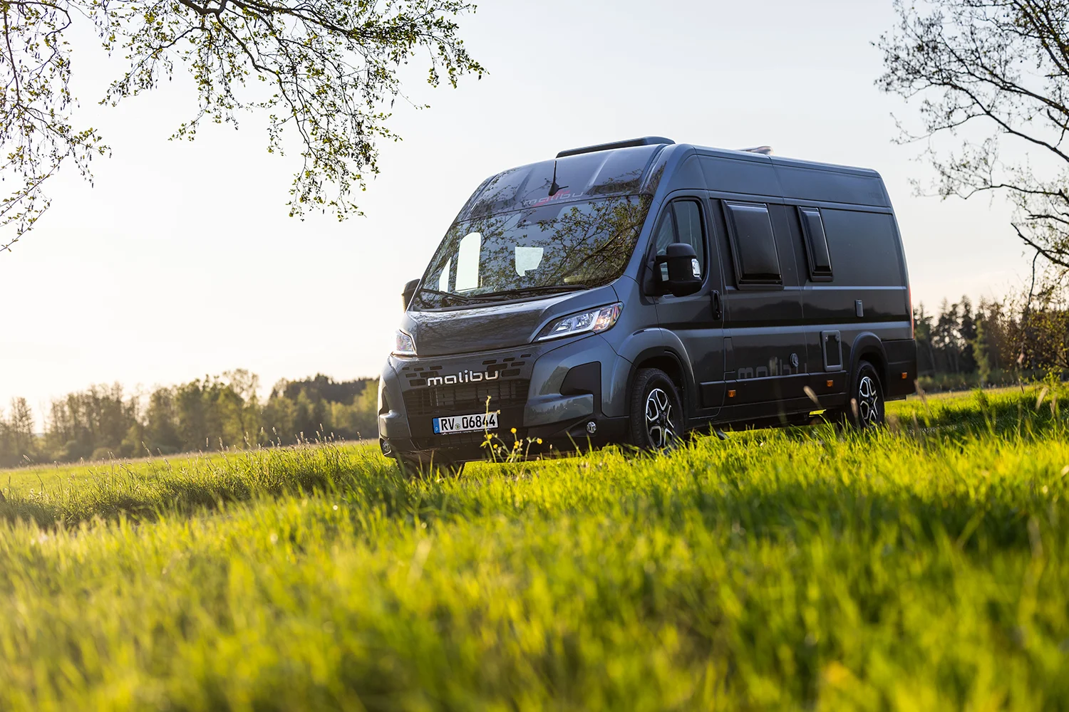 Malibu Relax Camper Van steht bei Sonnenuntergang auf einer grünen Wiese