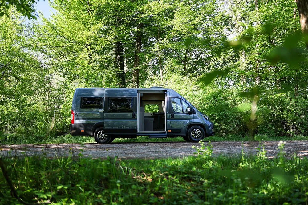 Malibu Relax Camper Van mit offener Schiebetür am Waldrand geparkt