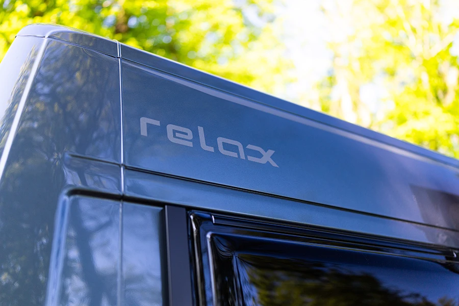 Detailaufnahme des Schriftzugs „relax“ am Malibu Fahrzeug im Sonnenlicht
