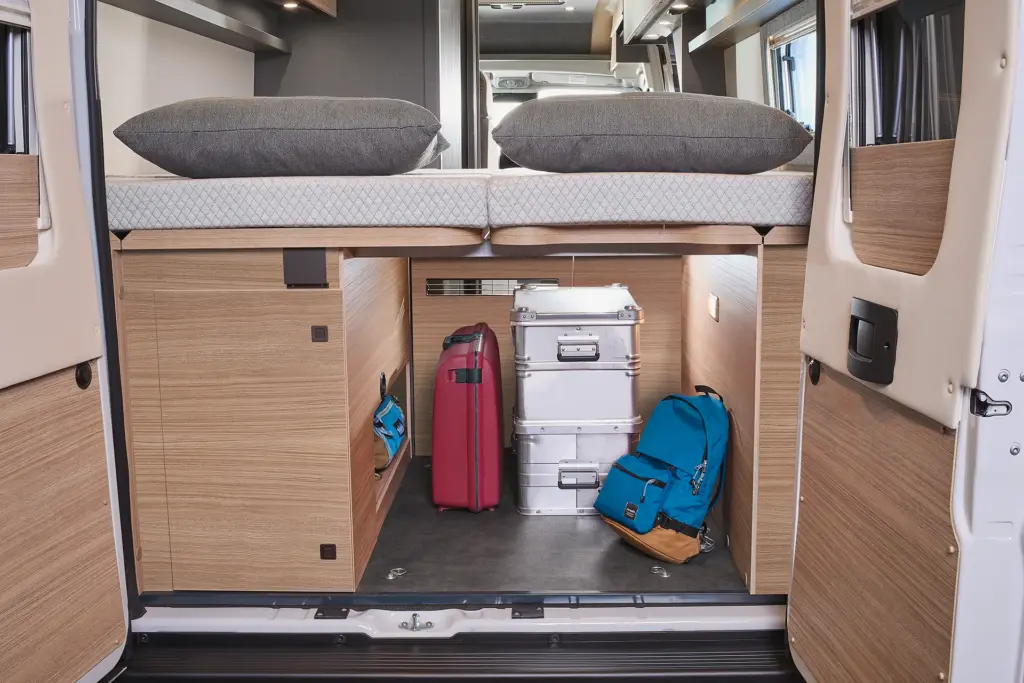 Espace de rangement généreux dans le Relax Camper Van, avec des valises et des sacs à dos rangés sous le lit