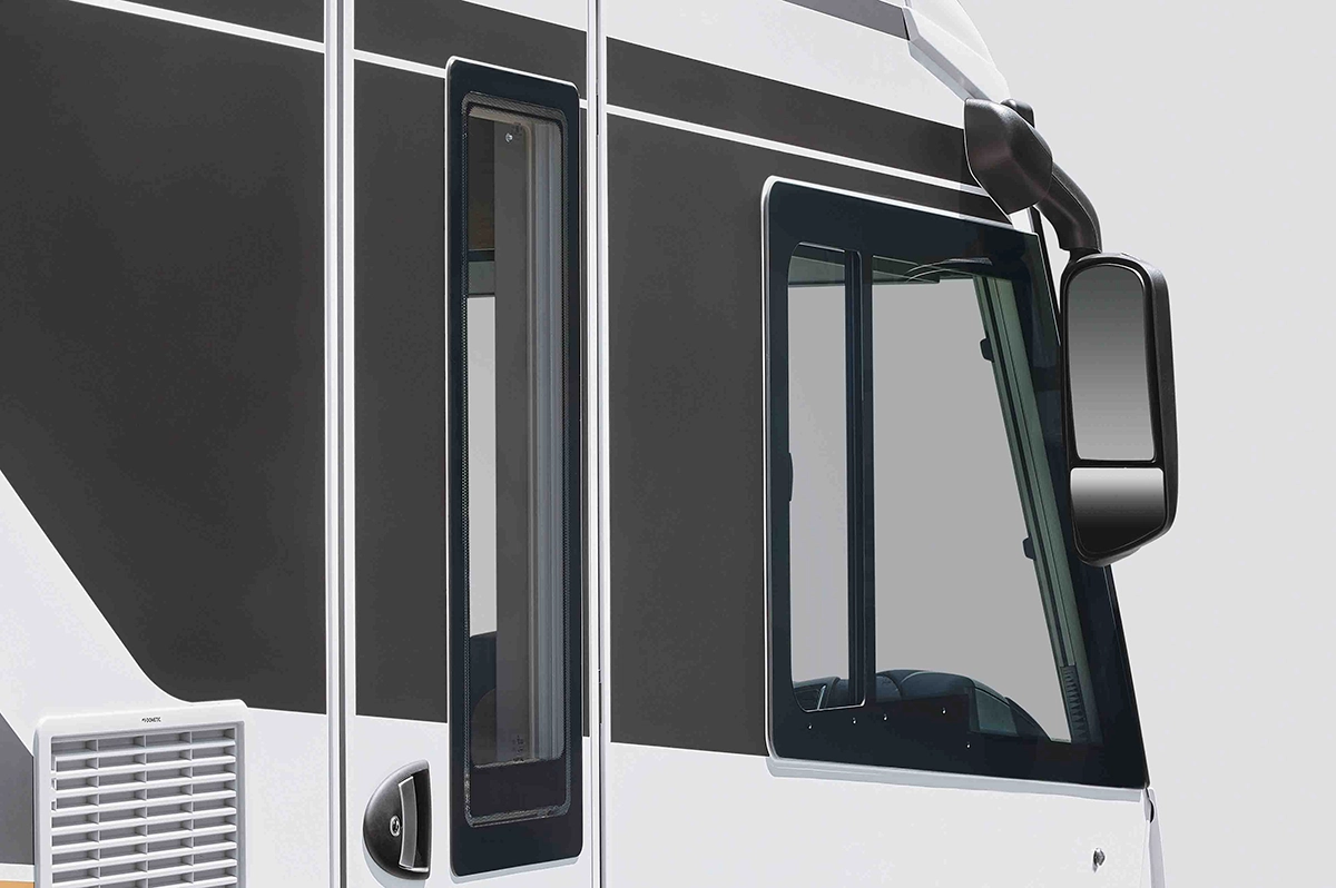 Nahaufnahme der Seiten- und Frontfenster eines modernen Wohnmobils, das ein schwarz-weißes Äußeres mit klaren Linien, einem Seitenspiegel und Reflexionen auf dem Glas zeigt.