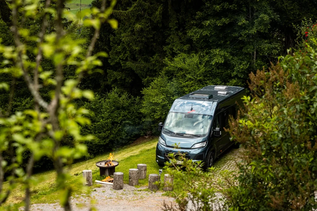 Ein Malibu relax steht auf einem Stellplatz umgeben von Natur und Bäumen.