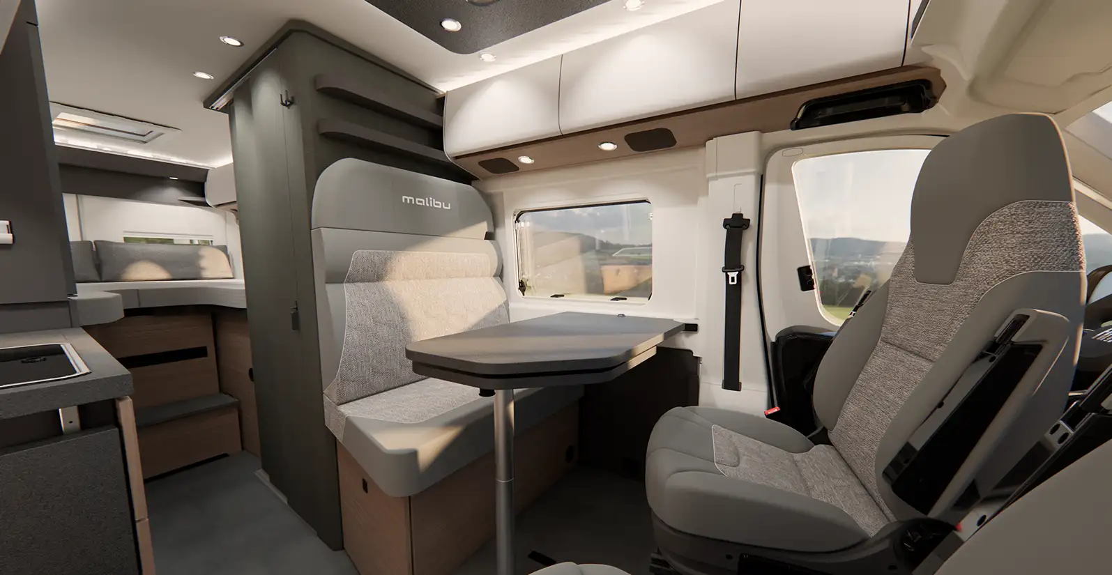 Ansicht auf den Innenraum eines Malibu Campervans mit Sicht auf die Küchenzeile mit moderner Arbeitsfläche, sowie die Längseinzelbetten im Heck des Fahrzeugs und der Sitzgruppe.