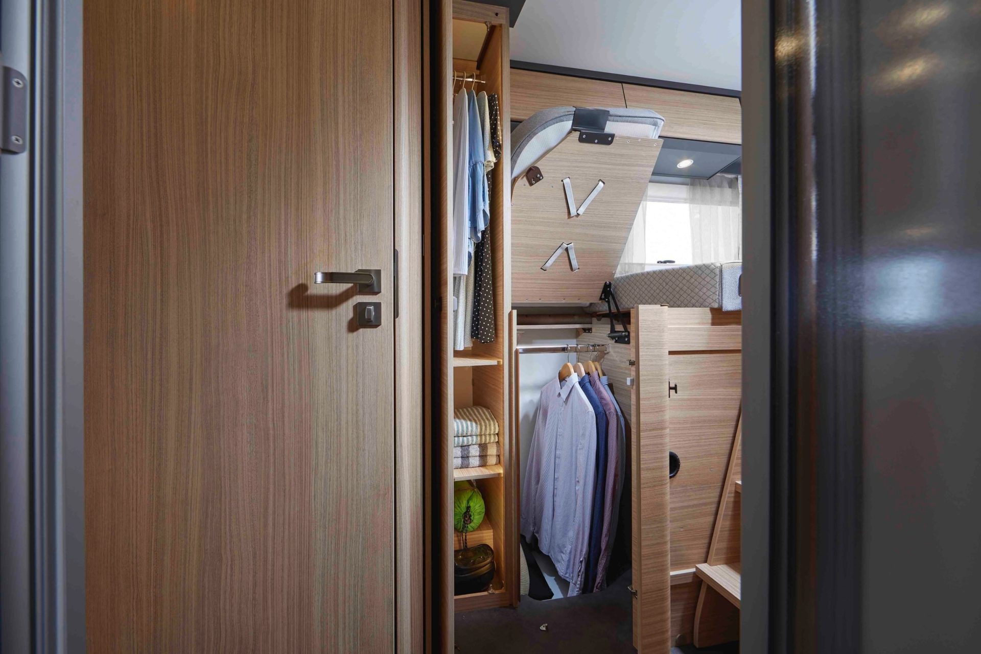 Sicht auf den raumhohen Kleiderschrank, mit aufgeklapptem Längseinzelbett