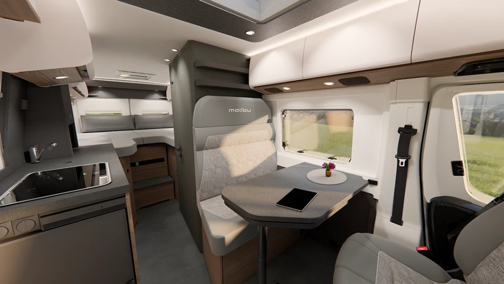 Innenansicht eines Malibu Cameprvans First Class - two rooms mit Blick auf die Küchenzeile mit moderner Arbeitsfläche, Längseinzelbetten im Heck, sowie die Sitzgruppe.