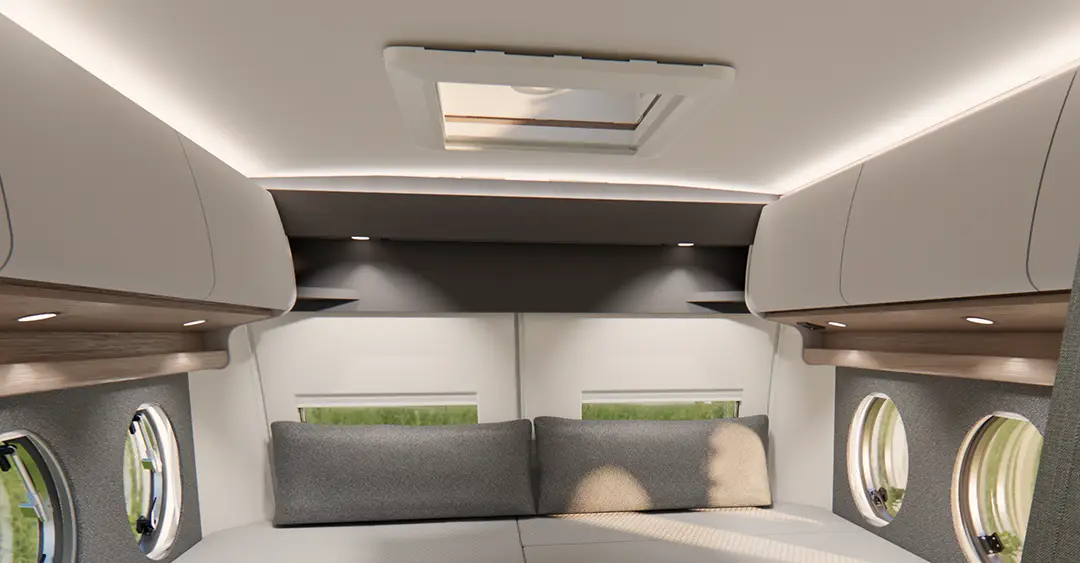 Ansicht der Längseinzelbetten eines Malibu Campervans mit jeweils zwei Bullaugen an jeder Seite, sowie Stauschränken über den Betten.