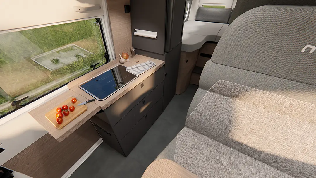 Ansicht der Küchenzeile eines Malibu Campervans mit ausklappbarer Arbeitsflächenerweiterung, sowie angrenzendem Kühlschrank und Längseinzelbetten.