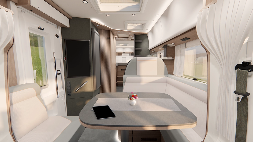 Modernes Wohnmobil-Interieur mit hellen gepolsterten Sitzen und einem Esstisch für vier Personen mit Salaten. Der Raum ist gut beleuchtet, mit Holzschränken, Regalen und einem Fenster mit Vorhängen, die eine gemütliche und organisierte Atmosphäre schaffen.